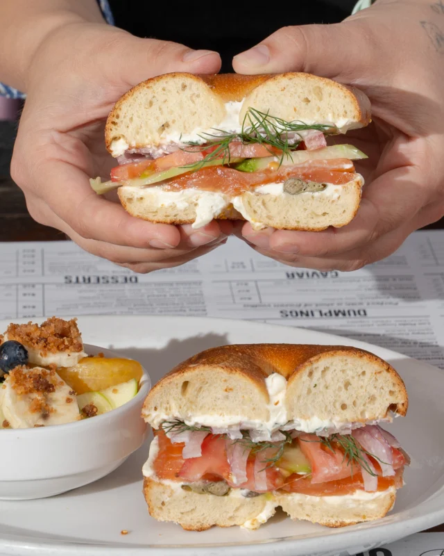 The Brooklyn Bagel Sandwich. House made lox, cucumber, tomato, sliced onion, schmear, capers, dill, and a Grossman’s Bakery bagel. Served with fresh fruit on the side, because balance. 
📸: @savery.media